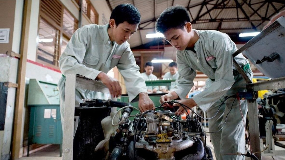 Trainees working together on an engine in a technical workshop